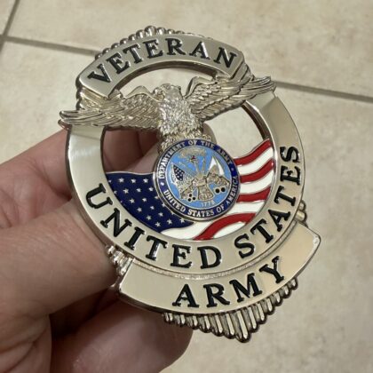 Close-up of a shiny metallic badge with an eagle in the center and the word VETERAN along the top rim.