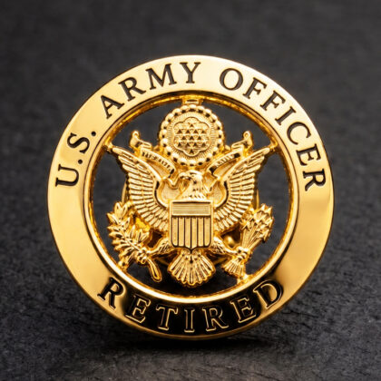 Gold circular pin with the U.S. Army Officer Retired insignia and eagle emblem.
