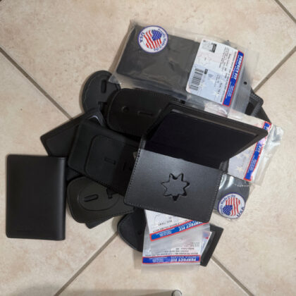 Pile of black leather wallets and card holders scattered on a beige tiled floor.